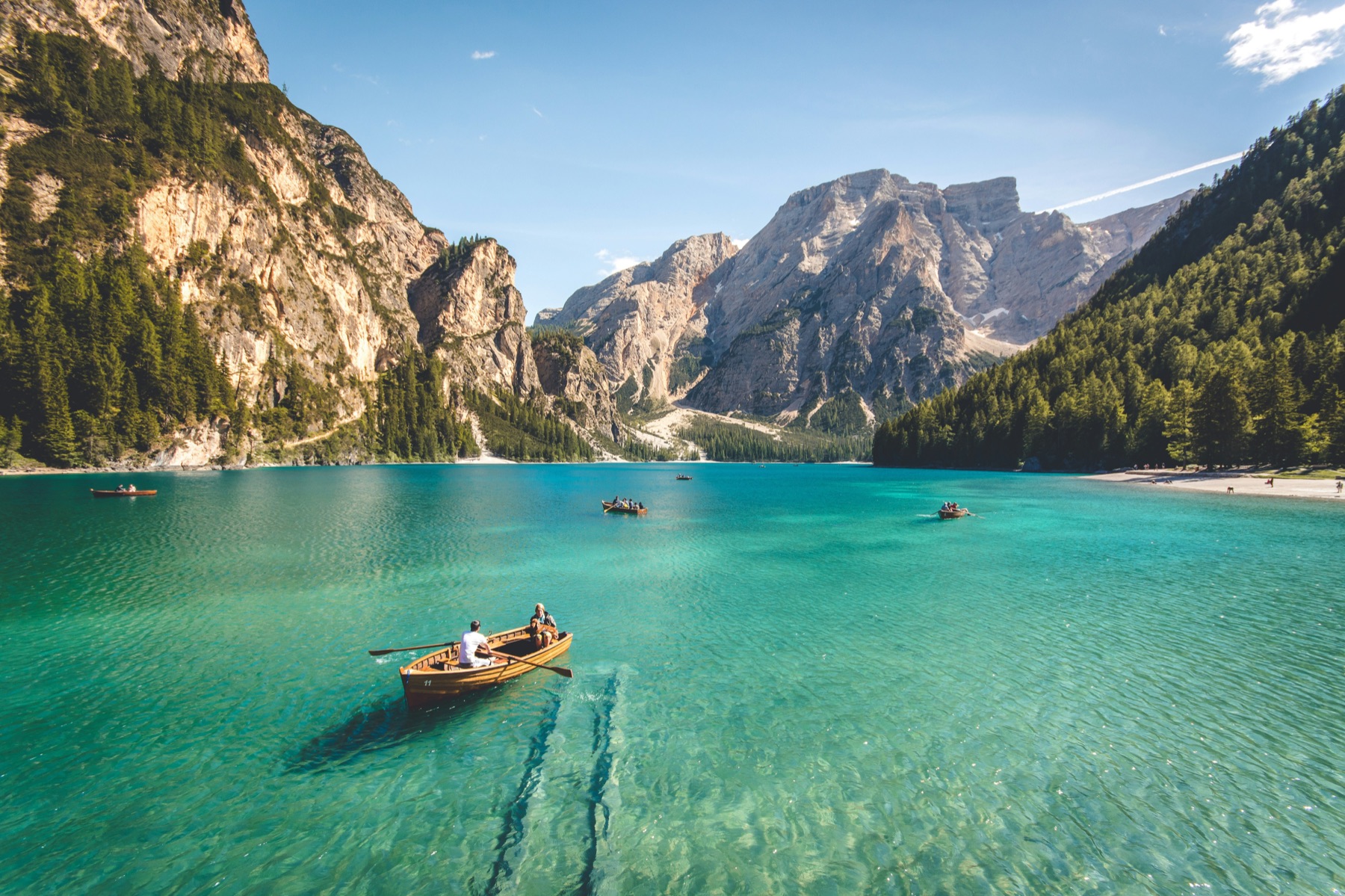 A wooden rowing boat on the clear turquoise water of an alpine lake, mountains behind
