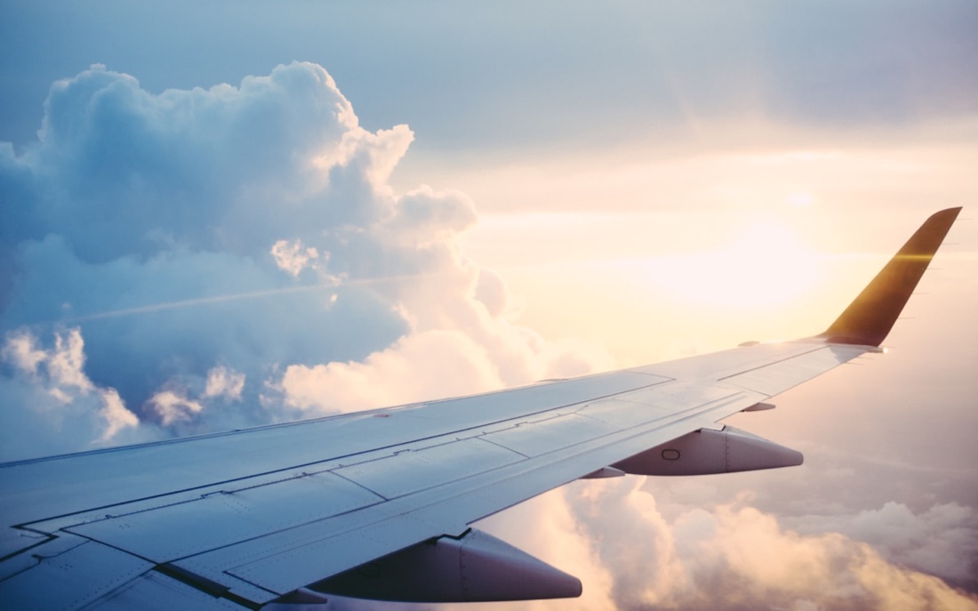 The wing of an airliner above a bank of clouds at sunrise